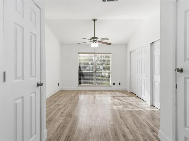 a view of empty room with wooden floor and fan
