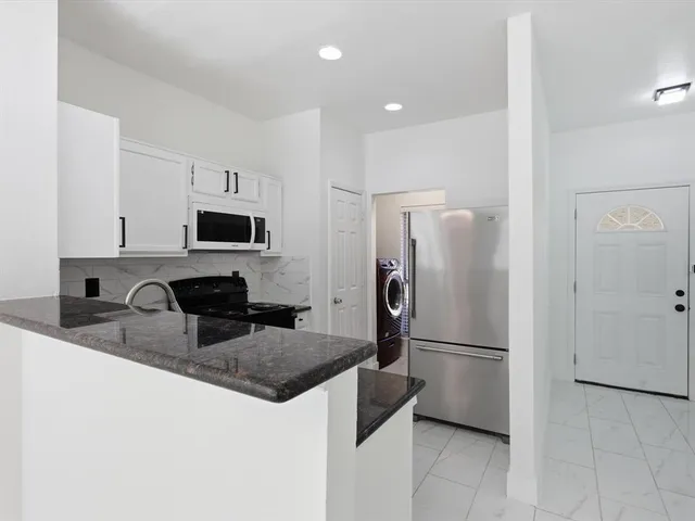 a kitchen with granite countertop a stove sink and cabinets