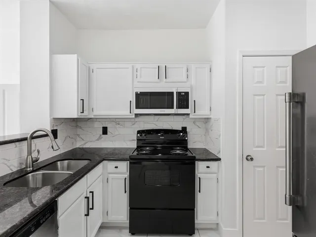 a kitchen with stainless steel appliances granite countertop white cabinets a stove top oven and granite counter tops