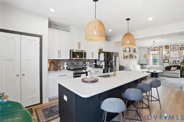 a kitchen with stainless steel appliances kitchen island granite countertop a sink a microwave refrigerator and chairs