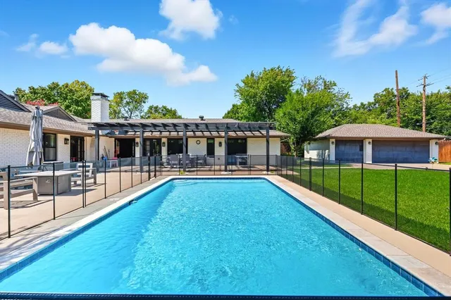 a view of house with swimming pool and a yard