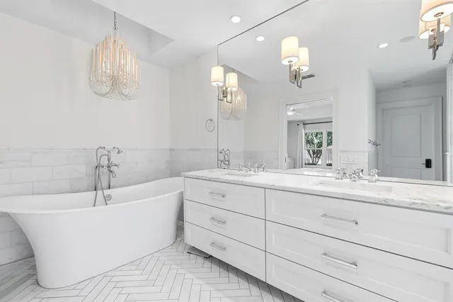 a bathroom with a bathtub a double vanity sink and a mirror