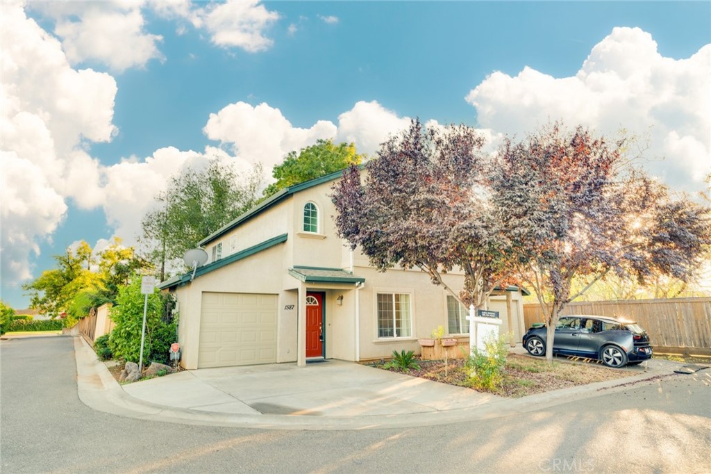a view of a white house with a small yard and a large tree
