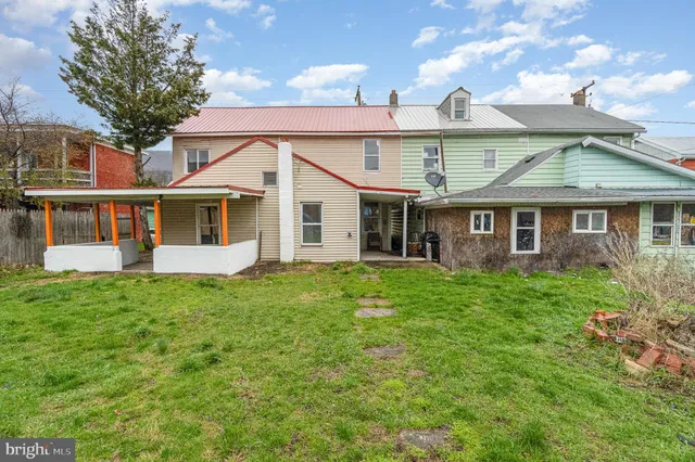 a view of a yard in front of a house with plants and large tree