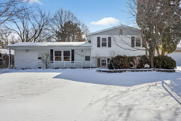 a front view of a house with a yard covered with snow