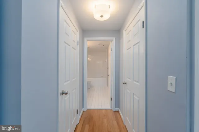 a view of a hallway with wooden floor and a bathroom