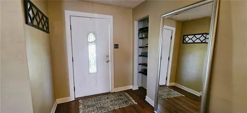 a view of a hallway with wooden floor and a livingroom