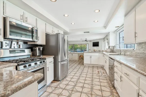 a kitchen with stainless steel appliances granite countertop a stove a sink and a refrigerator