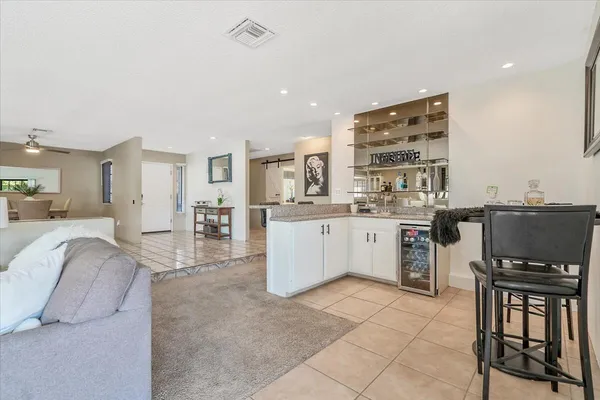 a living room with stainless steel appliances furniture a rug and a kitchen view