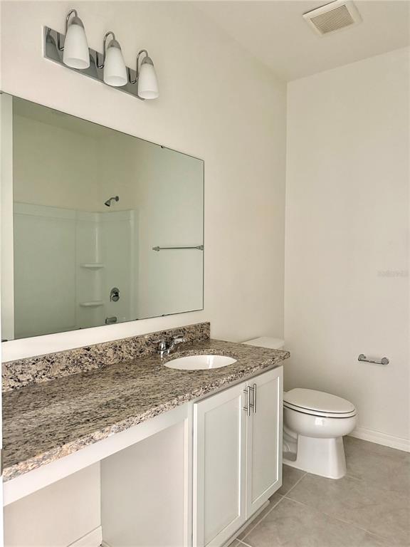 9023 Hooton Way Davenport, FL 33896 - Photo 16 of 25 a bathroom with a granite countertop sink a toilet and vanity