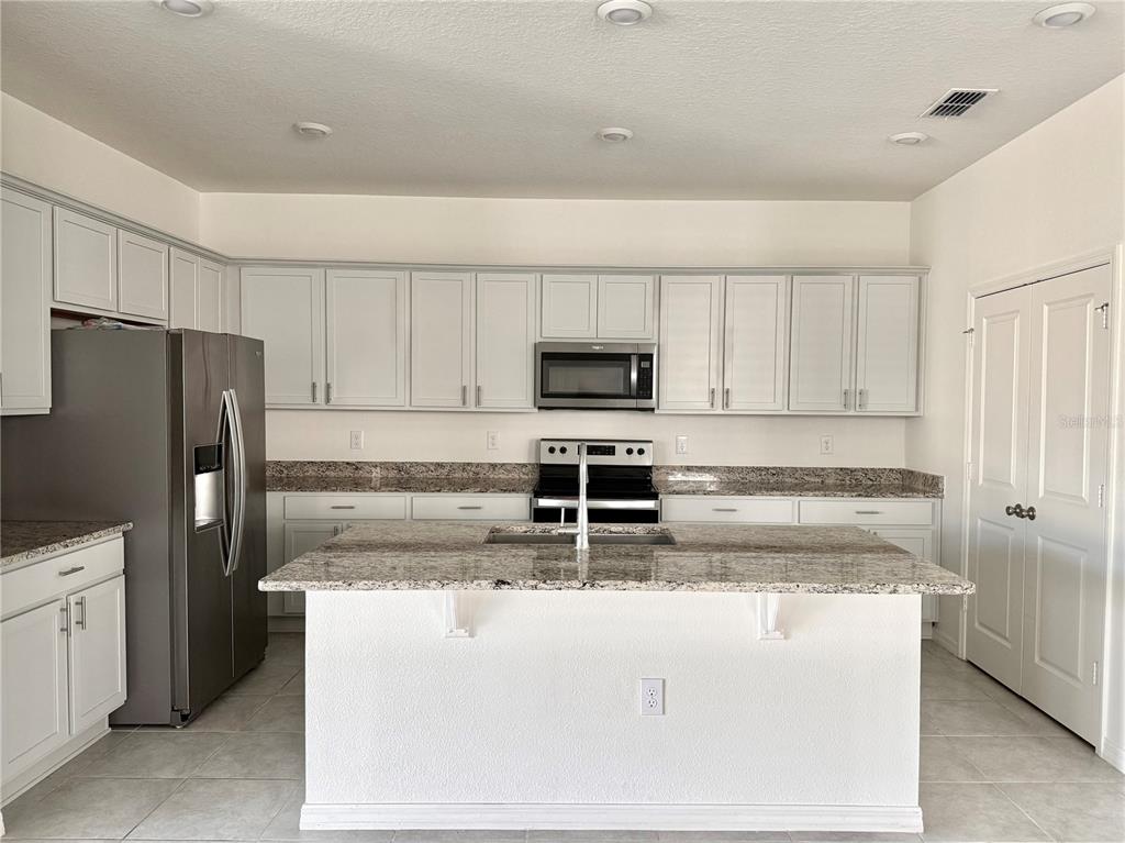 9023 Hooton Way Davenport, FL 33896 - Photo 3 of 25 a kitchen with kitchen island a sink stainless steel appliances and cabinets