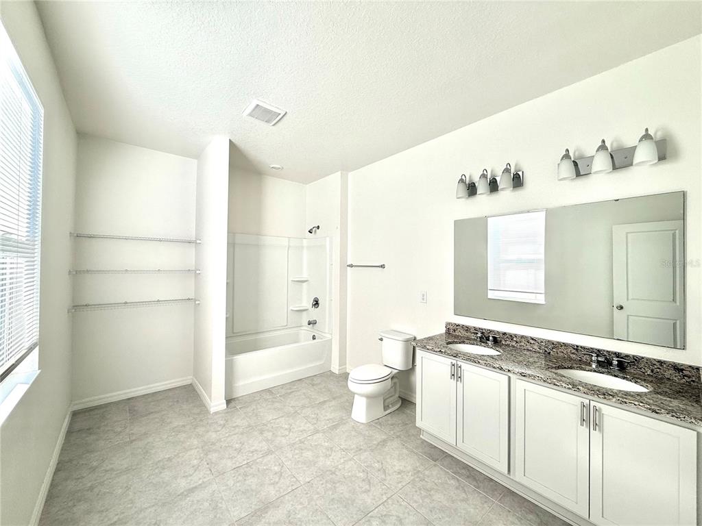 9023 Hooton Way Davenport, FL 33896 - Photo 10 of 25 a spacious bathroom with a double vanity sink toilet and shower