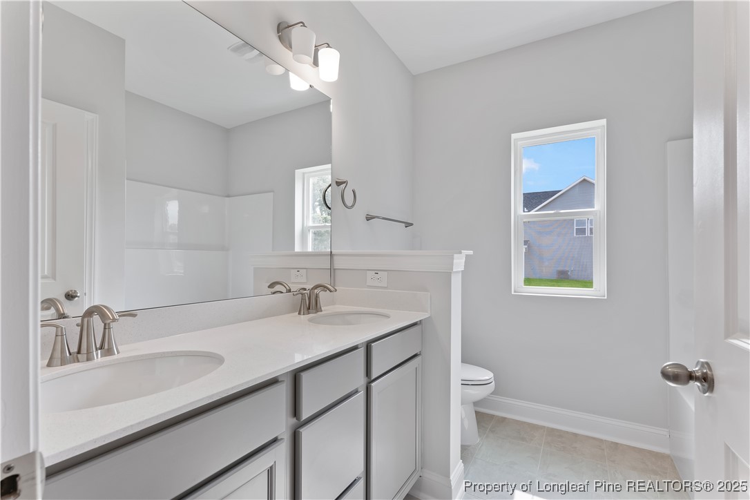 3117 Wolfpack Lane Eastover, NC 28312 - Photo 10 of 45 a bathroom with a granite countertop sink a toilet and a mirror
