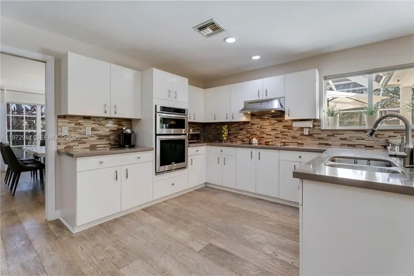 a kitchen with granite countertop white cabinets and white appliances