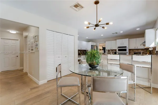 a kitchen with stainless steel appliances kitchen island granite countertop a dining table chairs and white cabinets
