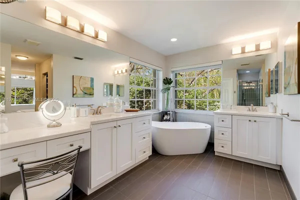 a spacious bathroom with a double vanity sink a mirror a bathtub and next to a window