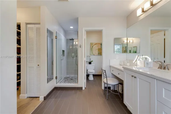 a spacious bathroom with a granite countertop sink a mirror and a shower