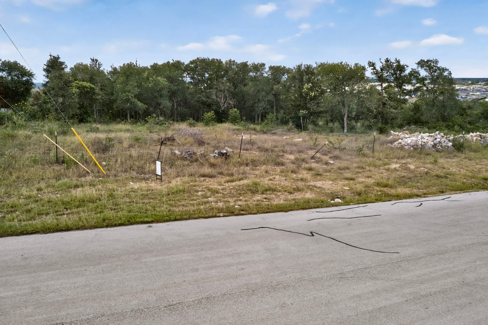 693 Santa Teresa Road Kyle, TX 78640 - Photo 15 of 20 A spacious, buildable lot awaits your vision, bordered by mature trees and a distant cityscape.