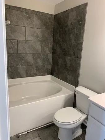 a white toilet sitting next to a bath tub
