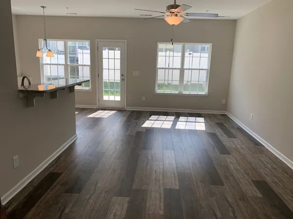 an empty room with wooden floor and windows