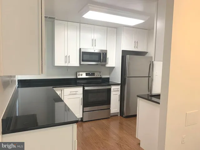 a kitchen with granite countertop white cabinets and stainless steel appliances