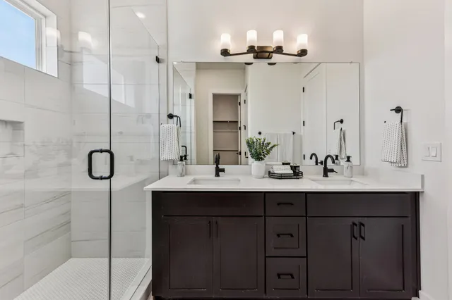 a bathroom with a double vanity sink a mirror and shower