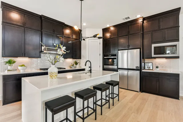 a kitchen with granite countertop a table chairs microwave and refrigerator