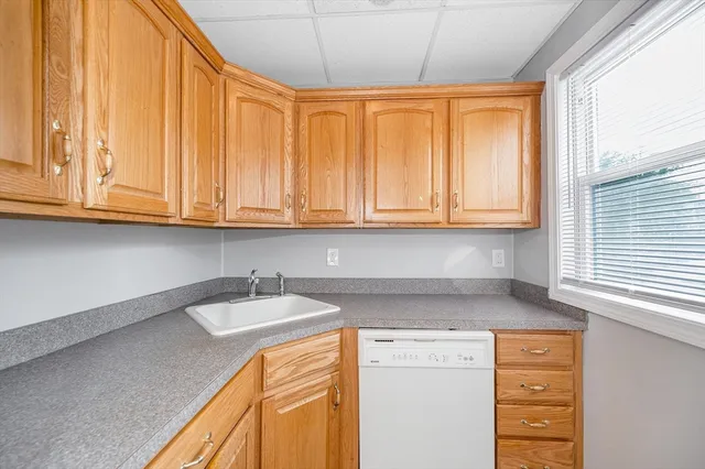 a kitchen with stainless steel appliances granite countertop a sink and dishwasher with wooden cabinets