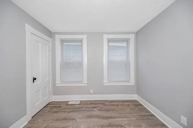 a view of an empty room with wooden floor and window