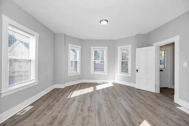 a view of an empty room with wooden floor and a window