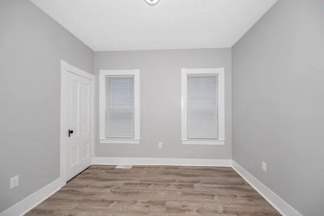 a view of an empty room with wooden floor and window