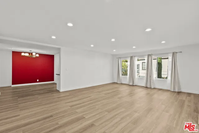 a view of an empty room with wooden floor and window