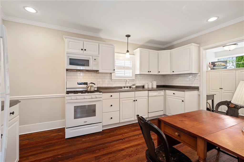 212 Pine Road Sewickley, PA 15143 - Photo 11 of 33 Updated kitchen with white cabinetry, tile backsplash, and hardwood floors, offering a clean and timeless aesthetic. Efficient layout supports everyday cooking and casual dining with easy connection to adjacent living spaces.