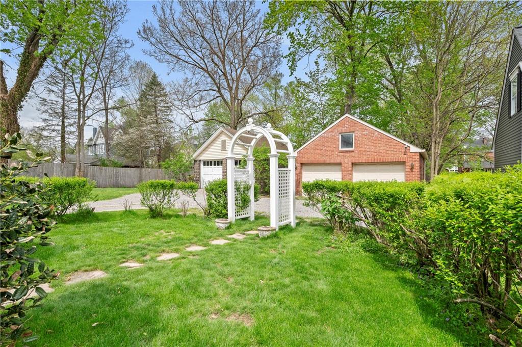 212 Pine Road Sewickley, PA 15143 - Photo 27 of 33 The backyard offers green space for outdoor enjoyment, framed by mature landscaping. A detached two-car garage with walk-up attic and additional parking provide flexibility for storage, hobbies, and everyday convenience.