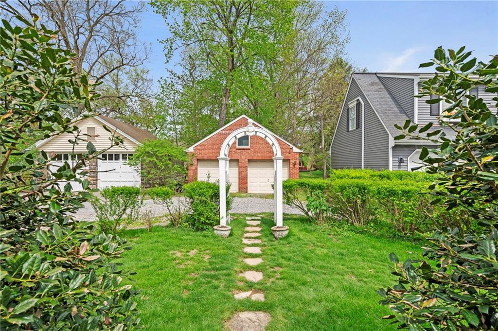 212 Pine Road Sewickley, PA 15143 - Photo 28 of 33 The backyard features a charming garden arbor and pathway, creating a defined outdoor focal point. A pleasant setting for gardening, relaxing, or enjoying time outside in a private, green space.