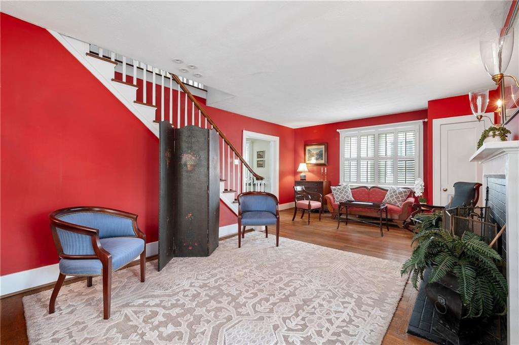 212 Pine Road Sewickley, PA 15143 - Photo 8 of 33 Bright, welcoming living room with hardwood floors, fireplace, and classic architectural details including plantation shutters and a staircase focal point. Spacious layout offers flexible seating and comfortable everyday living with easy flow for entertaining.