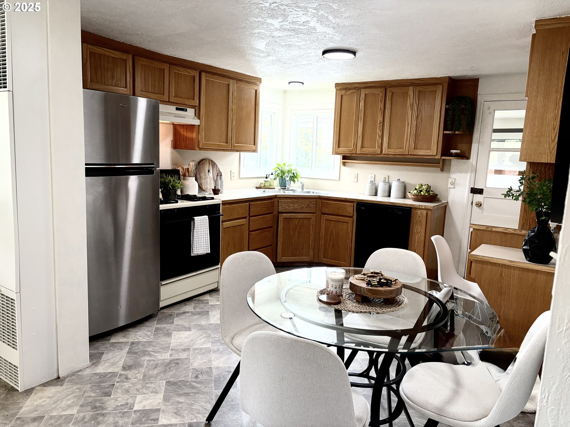 1730 Augusta Street Eugene, OR 97403 - Photo 10 of 11 a kitchen with stainless steel appliances granite countertop a refrigerator a stove a sink dishwasher a dining table and chairs