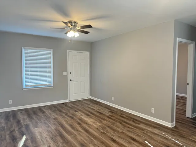 a view of a room with a ceiling fan and hardwood floor