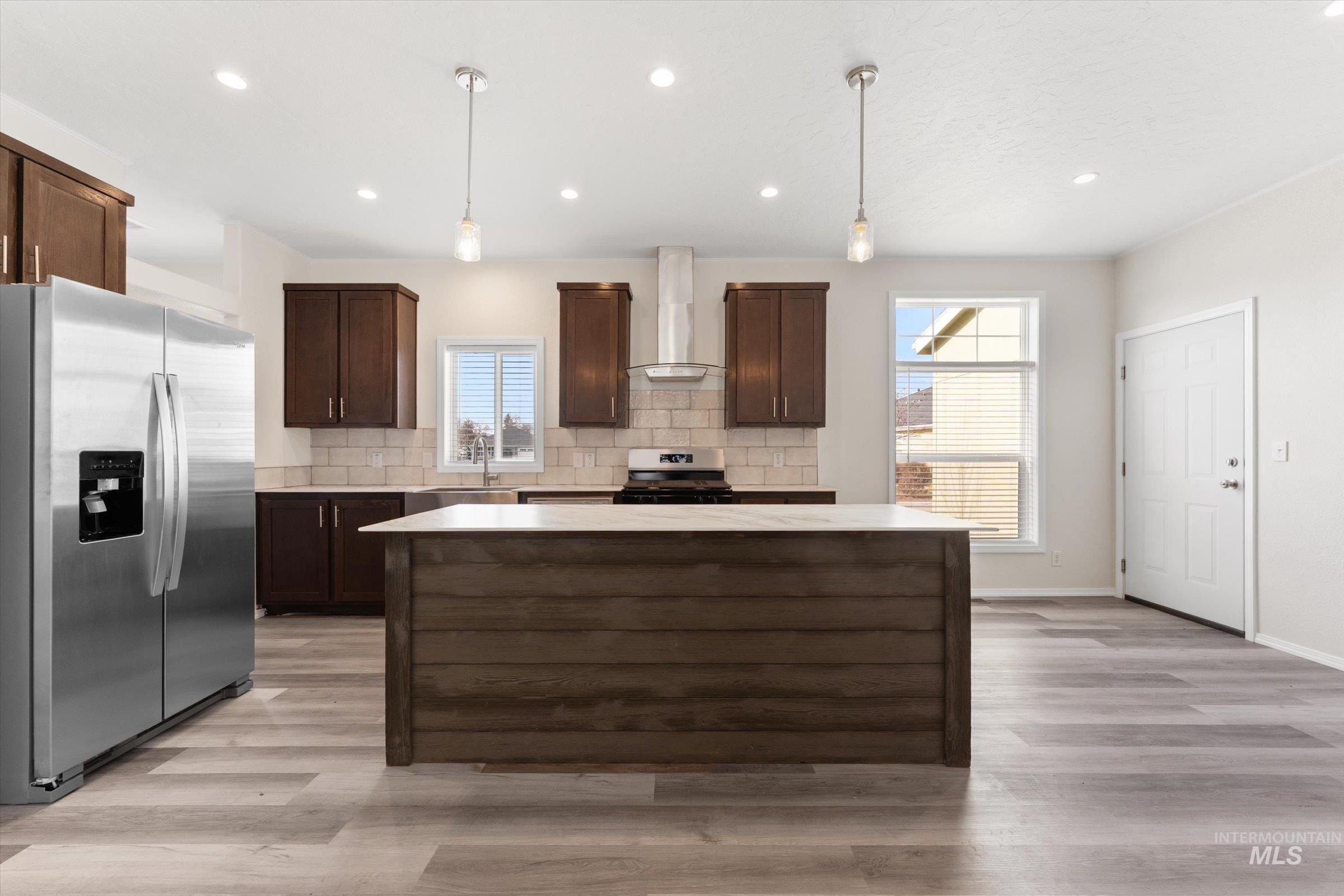 421 South Curtis Road, Unit 34 34 Boise, ID 83705 - Photo 3 of 22 Kitchen with dark brown cabinetry, stainless steel appliances, hanging light fixtures, a kitchen island, and tasteful backsplash