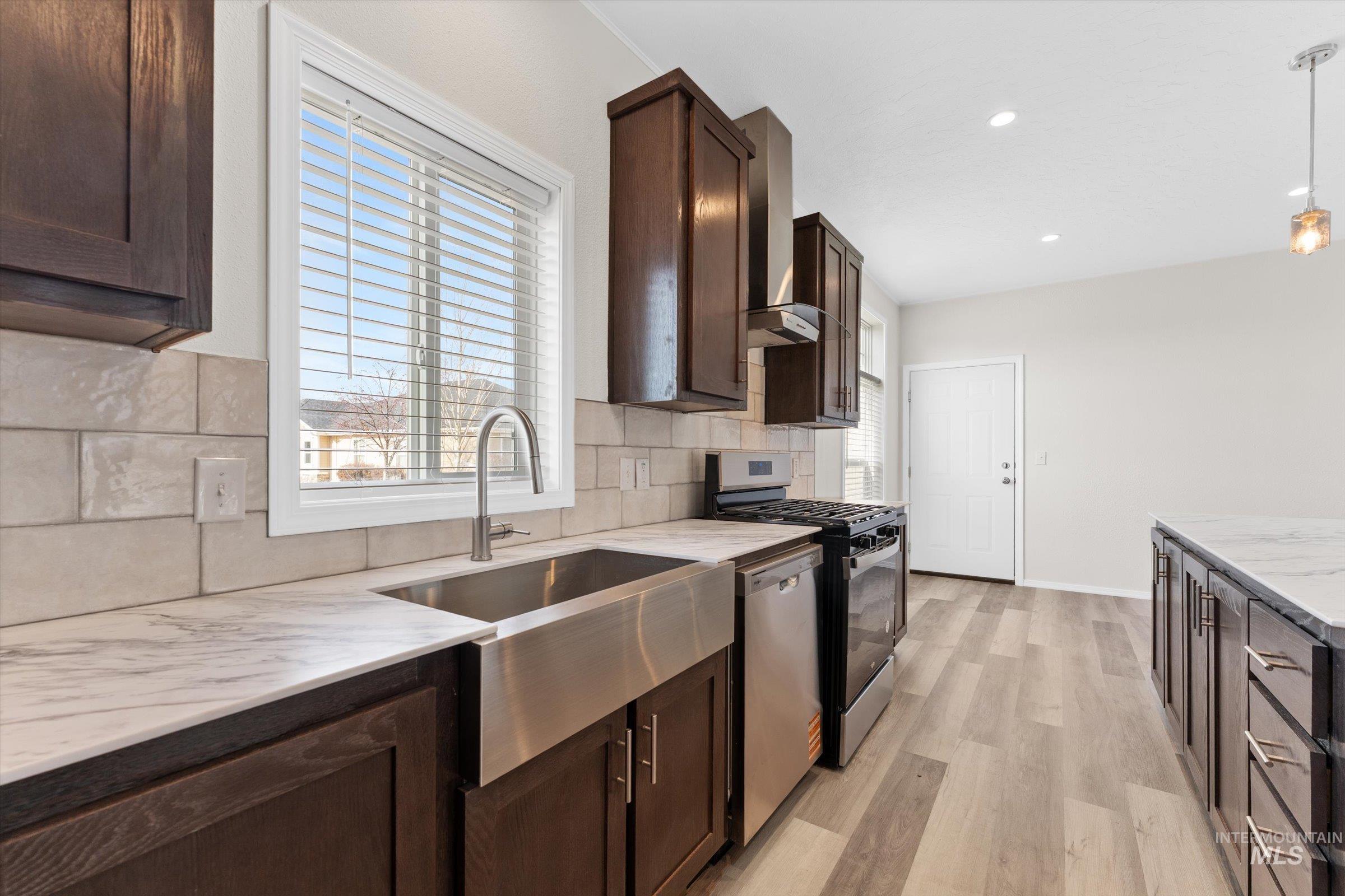 421 South Curtis Road, Unit 34 34 Boise, ID 83705 - Photo 5 of 22 Kitchen with dark brown cabinetry, stainless steel appliances, light wood-type flooring, backsplash, and light stone countertops