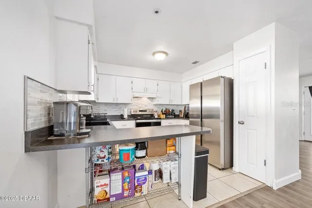 a kitchen with stainless steel appliances granite countertop a refrigerator a stove a sink and dishwasher with white cabinets