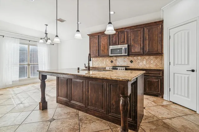 a kitchen with kitchen island granite countertop a stove a sink and a cabinets
