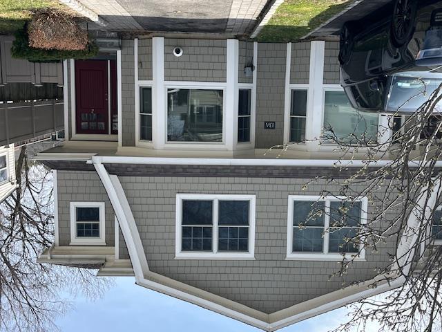 View of front of house featuring a shingled roof and fence