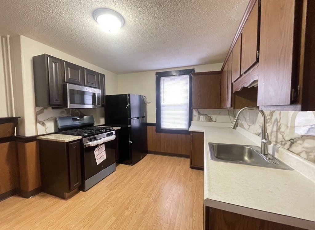 a kitchen with granite countertop a sink stove and refrigerator