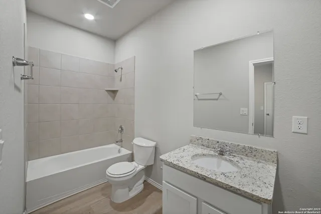 a bathroom with a granite countertop sink toilet and shower