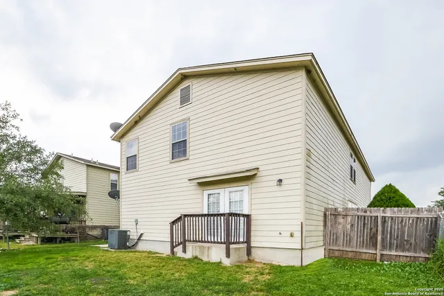 a view of backyard of house with wooden fence