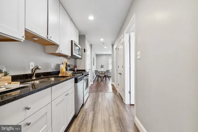 a kitchen with stainless steel appliances granite countertop lots of counter top space and wooden floor