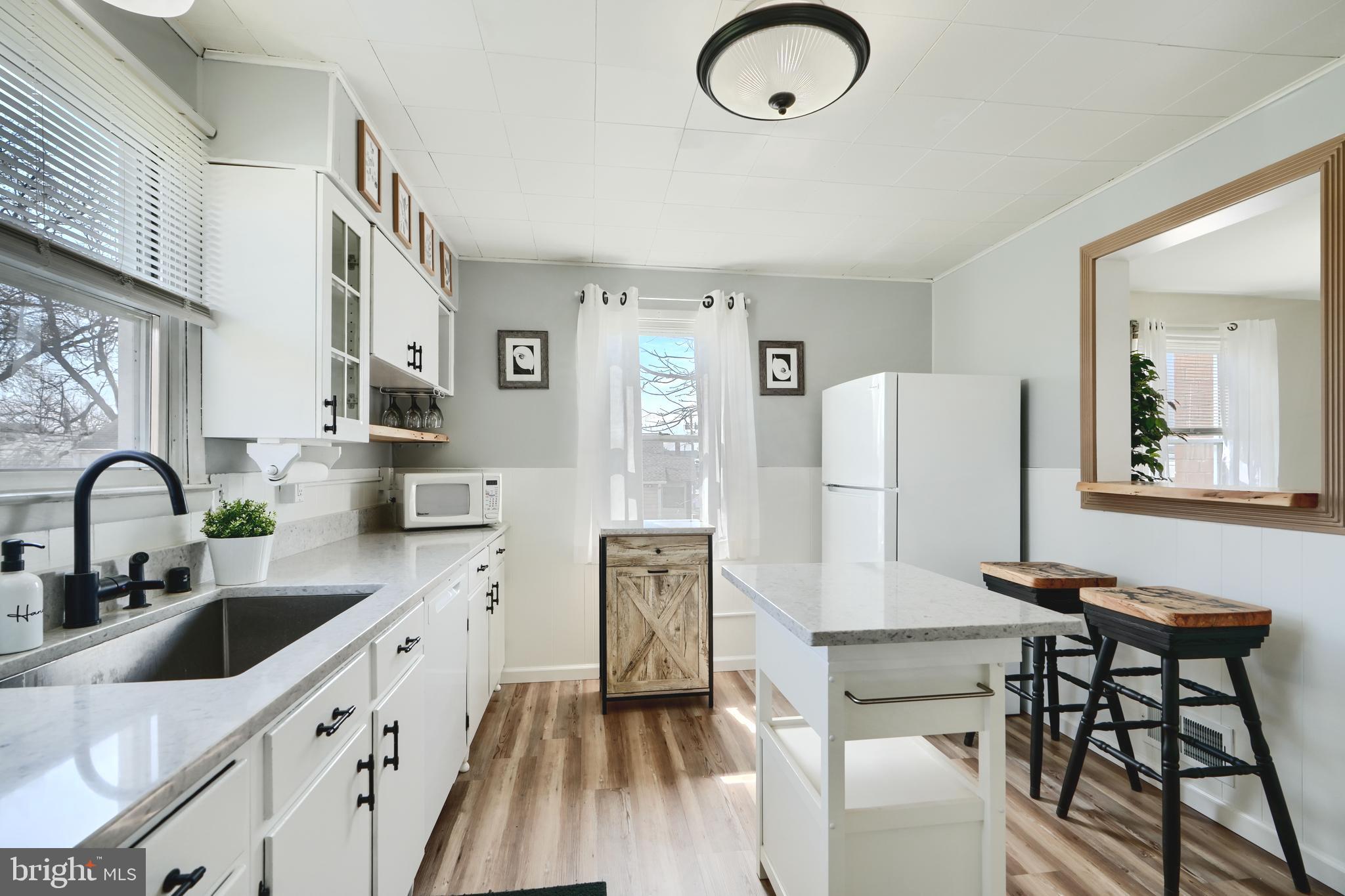 209 Middle River Road Baltimore, MD 21220 - Photo 11 of 35 a kitchen with stainless steel appliances a refrigerator a sink a stove and a dining table with wooden floor
