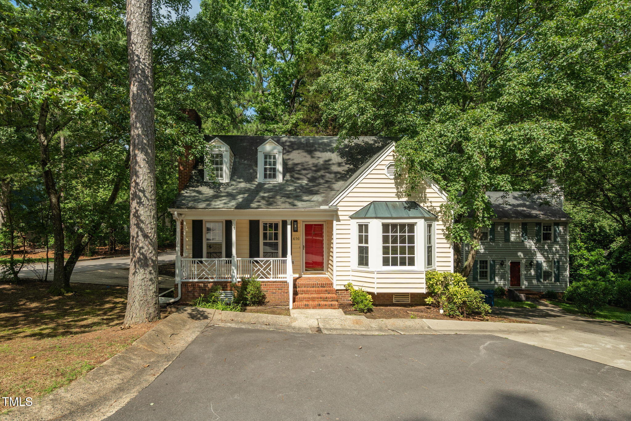 a front view of a house with a garden and tree