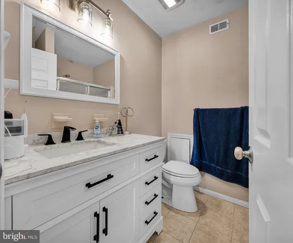a bathroom with a granite countertop toilet sink and mirror